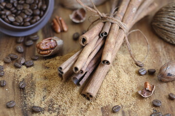 Cinnamon on coconut sugar with coffee and nuts on brown wooden background with selective focus