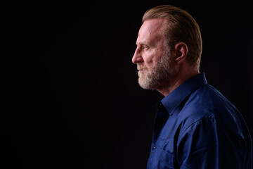 Mature handsome bearded man with blond hair against black background