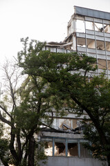 Remains of the destroyed industrial building. Demolished building surrounded with trees. Deconstruction of building. Destruction concept. Nature and mankind. 