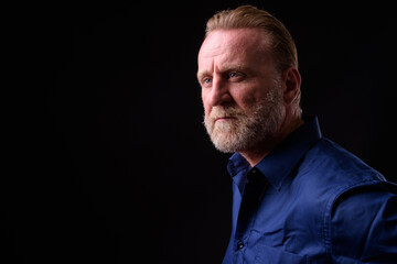 Mature handsome bearded man with blond hair against black background