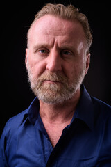 Obraz premium Mature handsome bearded man with blond hair against black background