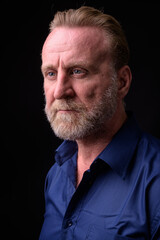 Mature handsome bearded man with blond hair against black background