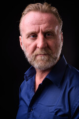 Fototapeta premium Mature handsome bearded man with blond hair against black background