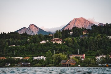 Großer beeindruckender Berg vor See bei Sonnenuntergang. Der Berg ist das rötliche Licht sichtbar.