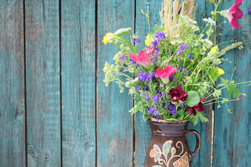 Wildflowers in an antique jug on a wooden background