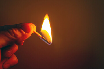 Hand holding a burning match at dusk