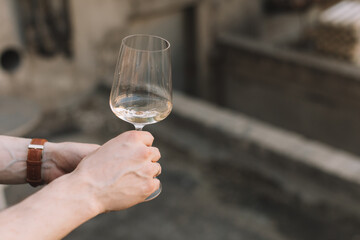 Man holding glass of white wine on the terrace. Copy space. Alcoholic drinks concept.