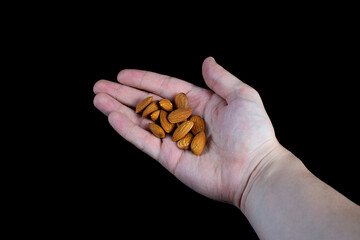 handful of almonds in the palm on a black background