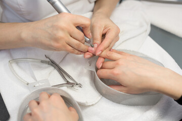 Manicurist doing hardware manicure to a young beautiful girl in the spa salon. Hardware manicure. Concept of body care