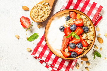 Fototapeta na wymiar Greek yogurt granola with fresh berries on white stone table.