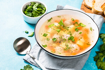 Meatballs soup with vegetables on blue.