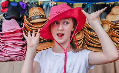 Funny portrait of a young girl in a pink cowboy hat  - goofy look on face with tongue out