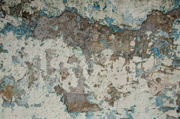 Old flaky plastered concrete wall. Texture of a stone wall with destroyed plaster with blue and light brown shades. Cracks, scrapes, peeling old paint and plaster. Old painted wall background.