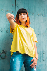 Alternative caucasian model with feminist orange hair in a yellow shirt on a blue wooden background in a badass attitude.