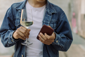 Young man using smart phone and holding glass of wine. Close up, outdoors, relax concept.