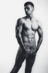 Fototapeta premium Male shirtless model with perfect body in jeans posing over white background. Close-up. Studio shot.