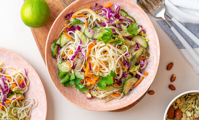 Vegetarian food. Salad with noodles, vegetables and sesame seeds in a bowl on a white served table top view. Delicious and healthy food.
