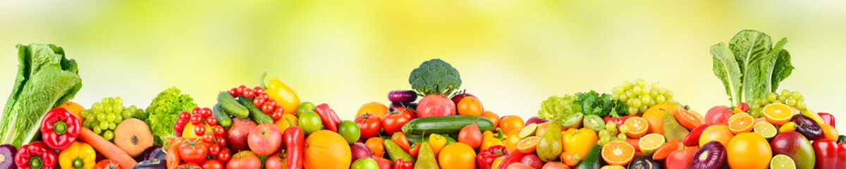 Panoramic photo fruits and vegetables on green natural blurred background.