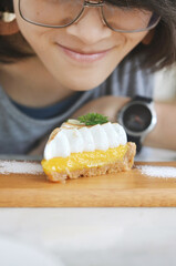 Woman looking at tasty lemon cheesecake on wooden table