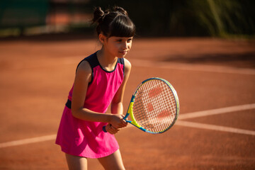 girl concentrated on tennis court and playing tennis