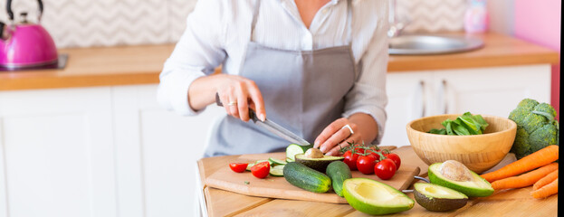 Obraz na płótnie Canvas Woman cook in apron cuts vegetables in kitchen