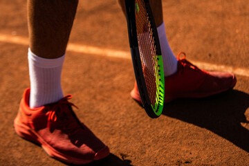 close-ups of two feet and a tennis racket on a clay tennis court