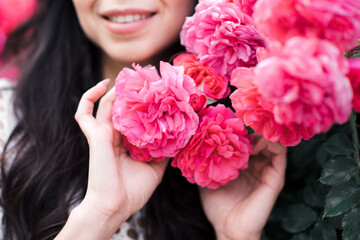 Naklejka premium Young girl holding pink fresh roses closeup. Summer season. Healthy lifestyle. 20s.