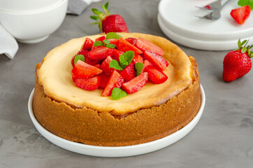 Homemade cheesecake New York with fresh strawberries on a white plate with coffee on a gray stone background. American cuisine.