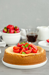 Homemade cheesecake New York with fresh strawberries on a white plate with coffee on a gray stone background. American cuisine.
