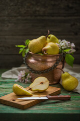 Ripe pears in a copper pot on a wooden old table, harvesting. Rustic style, still life
