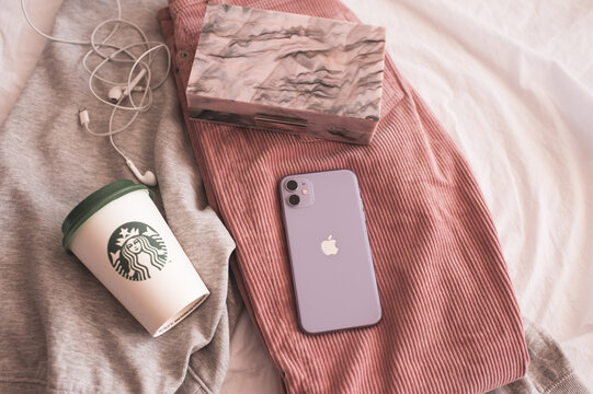 Moscow/Russia - July 23, 2020: Iphone 11 In Purple Shade With Starbucks Coffee Cup And Stylish Bag On Clothes In Bed Closeup. Top View.