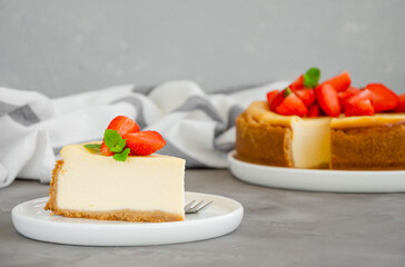 Homemade cheesecake New York with fresh strawberries on a white plate with coffee on a gray stone background. American cuisine.