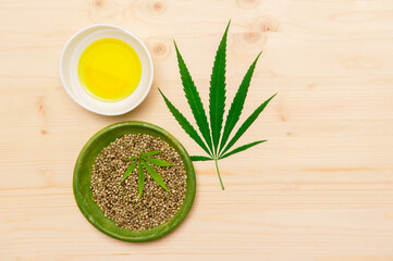 Green marijuana leaf, hemp seeds and cannabis oil on wooden background. Alternative medicine. Vegetarian food concept