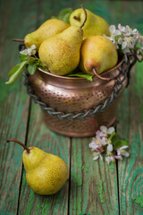 Ripe pears in a copper pot on an old wooden table. Harvesting, rustic style, vintage