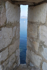 glimpse of the sea seen through a stone opening in the castle walls