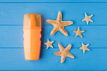 Fototapeta na wymiar Top above overhead view close-up photo of sunscreen and starfish isolated on blue wooden background with copyspace