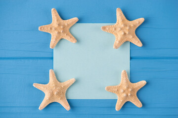 Top above overhead view close-up photo of a blank note with starfish isolated on blue wooden background with copyspace