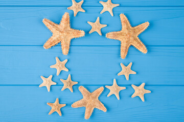 Top above overhead view close-up photo of a pattern of starfish isolated on blue wooden background with copyspace