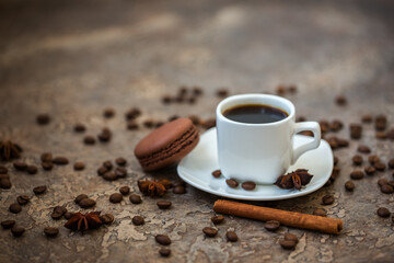 White cup of coffee with coffee beans, cinnamon and anise.