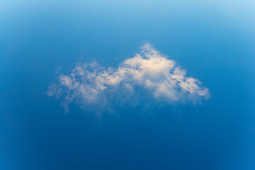 A uniquely shaped isolated white cloud on blue daylight sky background. Graphic design resource...