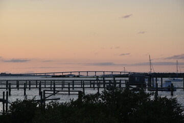 Bridge and Pier against a pink and orange sunset on a summer day.
