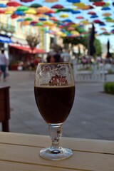 glass of dark beer on open air cafe table