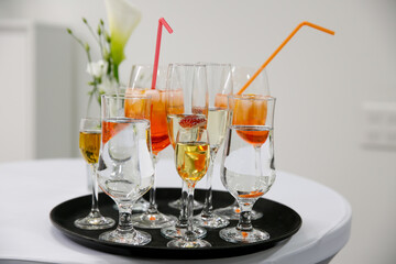 Rows of glasses with orange drink and ice cubes