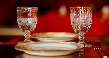 two beautiful glasses of glass stand on the table with a plate in the red interior 