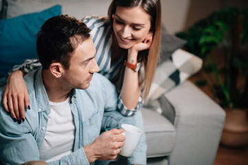 Portrait of a young couple in casual clothes on the couch in hugging each other