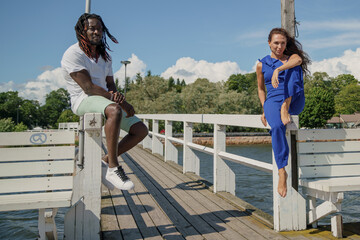 On a pier by the sea. couple outdoors. mixed pair of lovers, African man and European Caucasian woman.