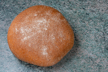 a round loaf of wheat bread with a baked shiny crust on the kitchen table