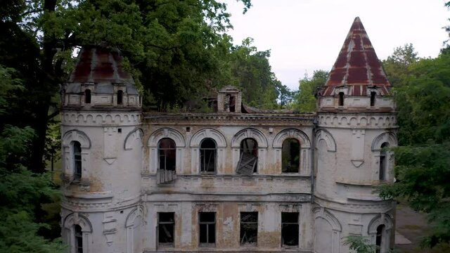 Abandoned 19th century palace or castle (manor or mansion house) with two towers and broken windows in Romanesque Revival architecture (or Neo-Romanesque) style. Aerial side view.