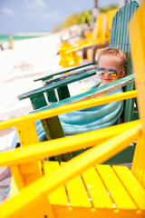 Little girl relaxing in colorful chair at beach