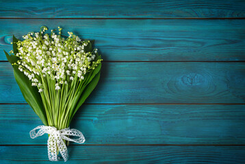 Beautiful bouquet of lily of the valley on a blue wooden background. Idea greeting card